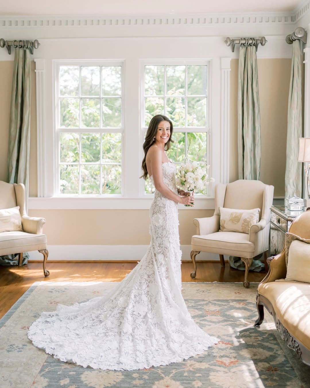 Bride in lace gown with long loose curls holding a white bouquet