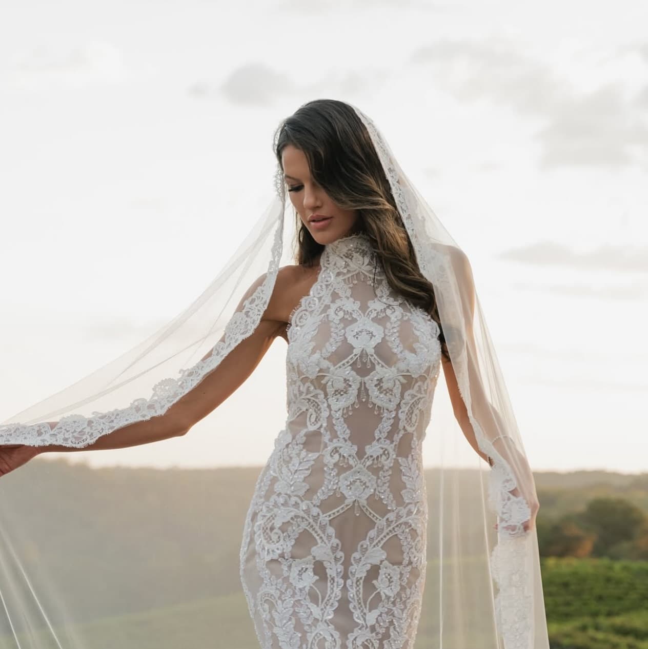 Bride with romantic loose waves and lace mantilla veil at sunset