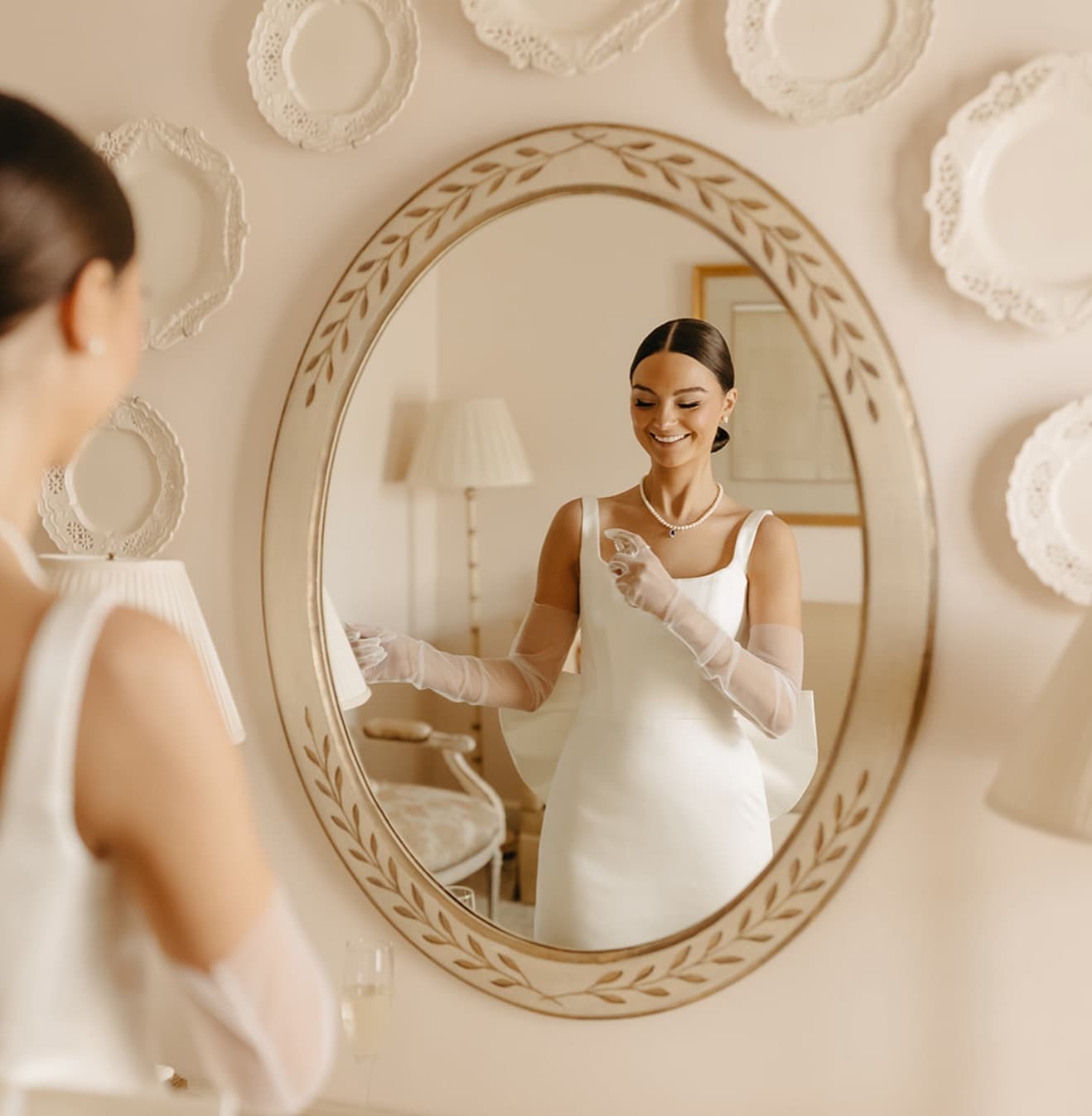 Bride with a sleek low bun and pearl necklace reflected in a mirror