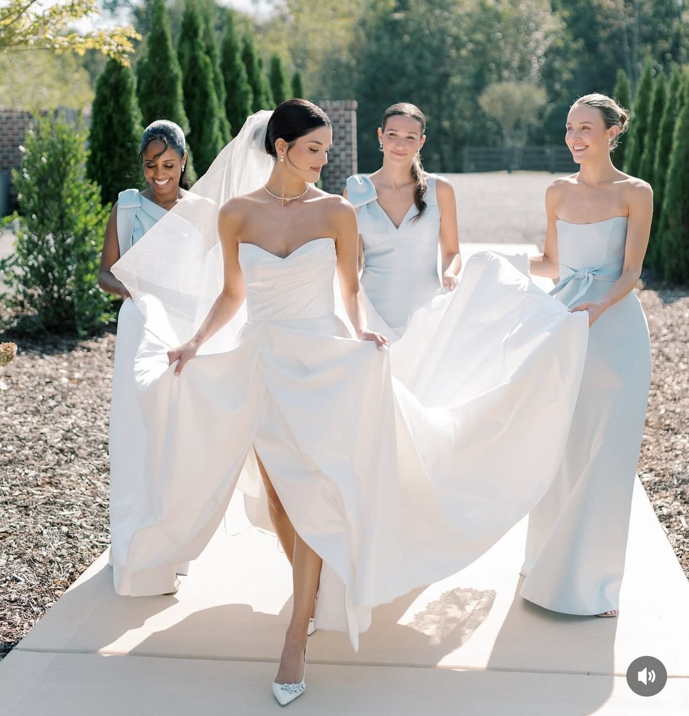 Bride with a sleek updo and veil walking with bridesmaids