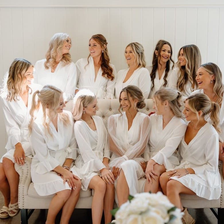 Bride with a low bun and bridal party in white robes getting ready